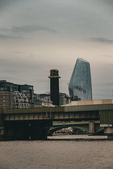 A high-angle view of a modern city skyline featuring several tall skyscrapers with glass facades reflecting the daylight. One of the prominent buildings has a curved, tapering design, while others are